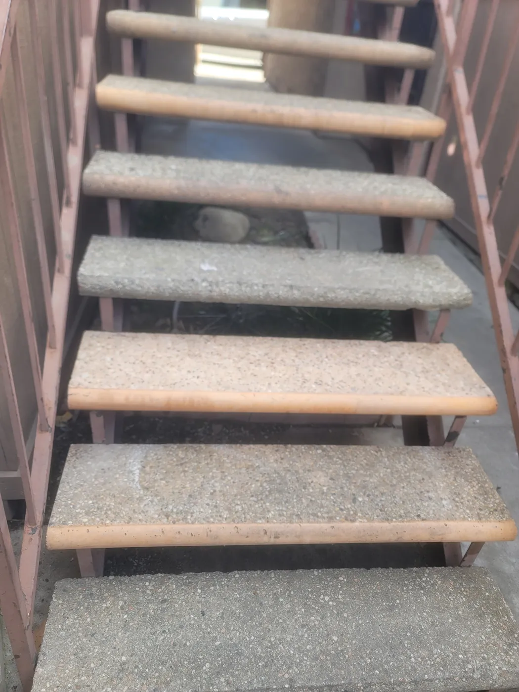 Close view looking up a flight of open-riser concrete stair treads carried on primed steel stringers